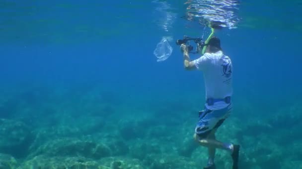 海でのプラスチック：水中操作者が魚が絡まって死んでいくビニール袋を撮影している。. — ストック動画