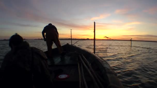 Σιλουέτα ενός ψαρά και μια βάρκα σε ένα δίχτυ ψαρέματος στο φόντο του ουρανού αυγής. — Αρχείο Βίντεο