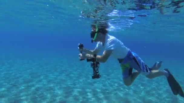 Un plongeur avec une caméra d'action plonge vers le fond sablonneux. — Video