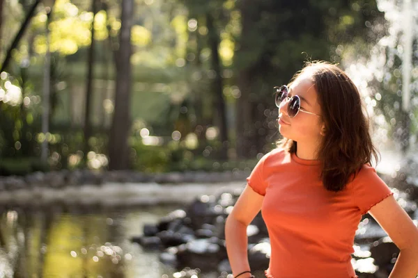 Chica de perfil con lentes obscuros en un parque