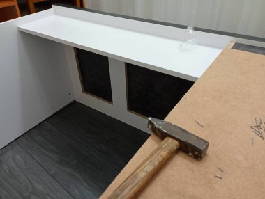 Mobilya montajı. Fotoğrafta, çekiç ve çiviler masanın arka panelini çekmek için kullanılıyor..