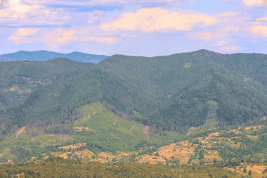 Ormanla kaplı uçsuz bucaksız dağ yamaçları vadideki ve tarlalardaki samimi bir köyü büyüleyici bir şekilde gözler önüne seriyor. Sıcak güneş ışığı ve gökyüzünün renkleri huzur ve huzur hissi yaratıyor..