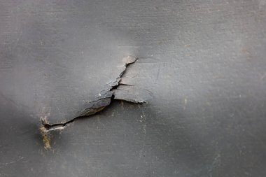 Siyah çatlamış bir yüzeyin soyut dokusu, eski deri veya asfalttaki çatlakları anımsatıyor. Aşınmayı, zamanı ve dayanıklılığı yansıtıyor..