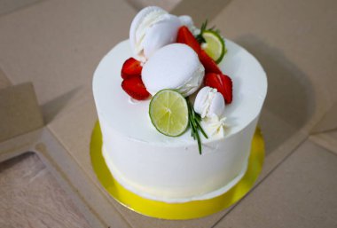 Taze böğürtlen, limon dilimleri ve kremayla süslenmiş beyaz bir pasta hassas ve taze bir atmosfer yaratıyor..