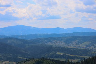 Ufuktaki mavi sisin içinde eriyen görkemli bir dağ silsilesi uzayın ve sükunetin sınırsızlığını ifade eden etkileyici bir manzara yaratır..