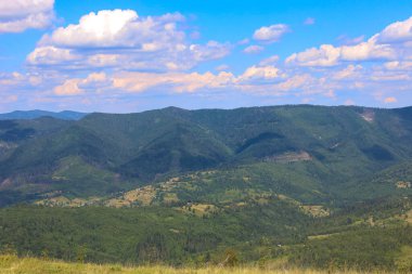 Yeşil ormanlarla kaplı uçsuz bucaksız dağ yamaçları doğanın huzur ve ihtişamını yansıtan etkileyici bir manzara yaratır..