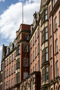 Bulutlu mavi gökyüzünün altında sayısız penceresi olan uzun, kırmızı tuğlalı binaların yan görüntüsü, İngiltere 'nin Tyne kentindeki Newcastle' da yer alan pencere ve yatakhaneler gibi mimari detaylar içeriyor..