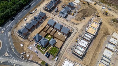 Kısmen inşa edilmiş ve tamamlanmış evler, inşaat ekipmanları ve İngiltere 'nin Catterick kentindeki Miller Evleri' ndeki işlenmemiş arazinin havadan görüntüsü..