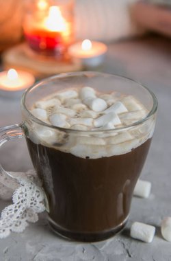 Mum ışığında bir fincan kakao ve bir marşmelov.