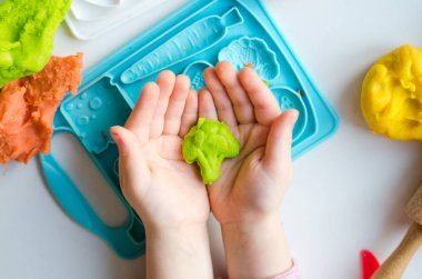 Renkli kil ile çocuğun el. Çocuk oyun ve oyun hamuru vagetables oluşturma. Modelleme kil kalıplama kız. Kil ev