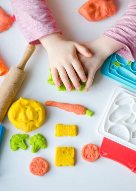 Renkli kil ile çocuğun el. Çocuk oyun ve oyun hamuru vagetables oluşturma. Modelleme kil kalıplama kız. Kil ev