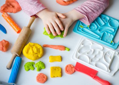 Renkli kil ile çocuğun el. Çocuk oyun ve oyun hamuru vagetables oluşturma. Modelleme kil kalıplama kız. Kil ev