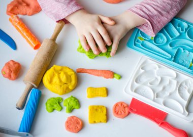 Renkli kil ile çocuğun el. Çocuk oyun ve oyun hamuru vagetables oluşturma. Modelleme kil kalıplama kız. Kil ev