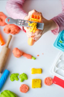 Renkli kil ile çocuğun el. Çocuk oyun ve oyun hamuru vagetables oluşturma. Modelleme kil kalıplama kız. Kil ev