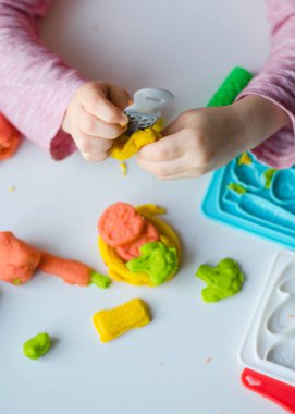 Renkli kil ile çocuğun el. Çocuk oyun ve oyun hamuru vagetables oluşturma. Modelleme kil kalıplama kız. Kil ev