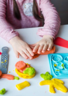 Renkli kil ile çocuğun el. Çocuk oyun ve oyun hamuru vagetables oluşturma. Modelleme kil kalıplama kız. Kil ev