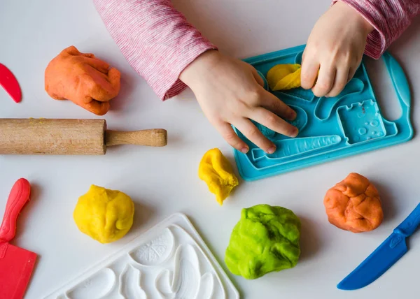 Child\'s hands with colorful clay. Child playing and creating vagetables from play dough. Girl molding modeling clay. Homemade clay