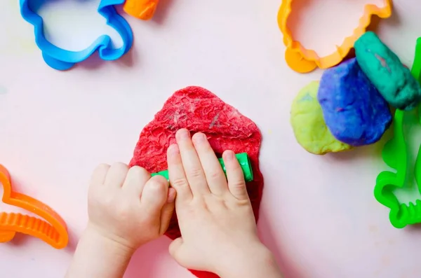 Çocuk elleri renkli kille oynuyor. Ev yapımı plastik.