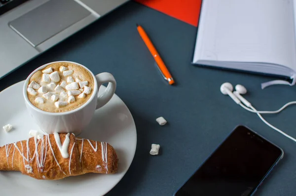 Creative flat lay of workspace desk, composition with notebook, coffe and croissant