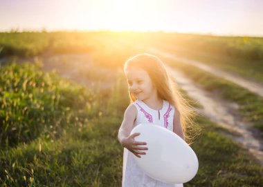 Beyaz kalp balon çayır alanında olan küçük kız. Mutlu sevgililer günü ve anneler günü kavramı. Yumuşak odak