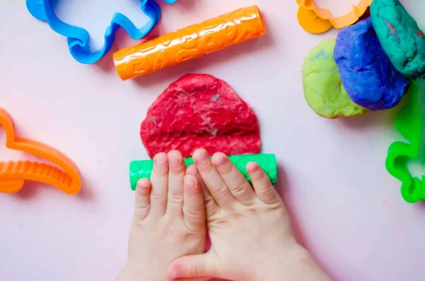 Çocuk elleri renkli kille oynuyor. Ev yapımı plastik.