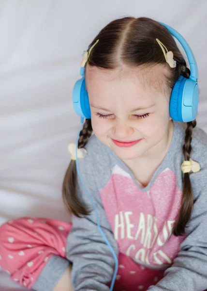 Little Girl Blue Headphones Holding Smart Phone Hands Sitting Bed — Stock Photo, Image