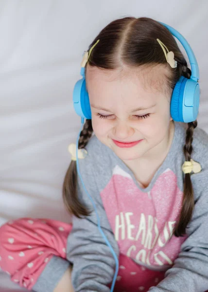 Niña Con Auriculares Azules Sosteniendo Teléfono Inteligente Las Manos Sentada — Foto de Stock