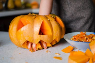 Cadılar bayramı, dekorasyon ve tatil konsepti için balkabağı oydum. Küçük kız evde balkabağı ya da balkabağı kabağı oyuyor. Helloween konsepti