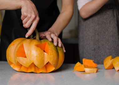 Cadılar bayramı, dekorasyon ve tatil konsepti için balkabağı oydum. Küçük kız ve annesi evde balkabağı ya da balkabağı kabağı oyuyorlar. Helloween konsepti