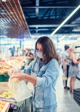 Süpermarkette maskeli güzel bir kız alışveriş yapıyor.