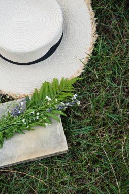 Yaz çiçekleri, eski kitap ve hasır şapka. Rahatlama zamanı, yaz mevsimi konsepti