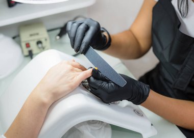 Manikür ustası kuafördeki müşteriye manikür yapıyor. Neil önemsiyor. Kapat.