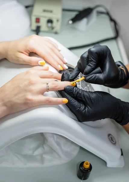 Master of manicure makes manicure to the client in the salon. Neil care. Close up