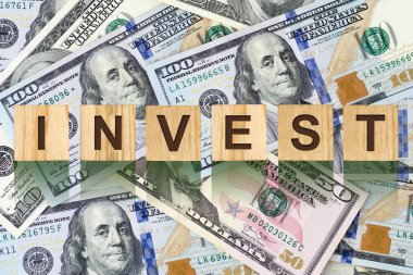 Word, mektup ahşap yapı taşları dolarlarına arka planı üzerinde Invest oluşur. Kavram iş, finans. Arka planlar.