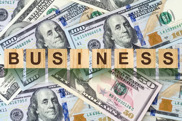 Word, Business composed of letters on wooden building blocks against the background of dollar bills. Concept business, finance. Backgrounds.