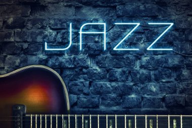 Vintage gitar ve bir neon Yazıtı caz ve arka plan üzerinde eski bir tuğla duvar. Konsept müzik.