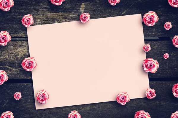 Ahşap bir masa üzerinde güzel pembe gül ile boş levha. Metin için yer. kopya alanı.