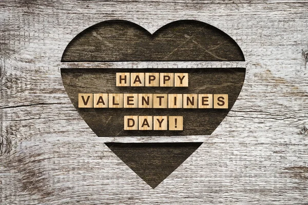 Dark wooden heart on a gray wooden background. Concept for Valentines Day. — Stock Photo, Image