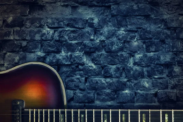 Old vintage jazz guitar on a brick wall background. Copy space. Background for concerts, festivals, music schools. Art, music