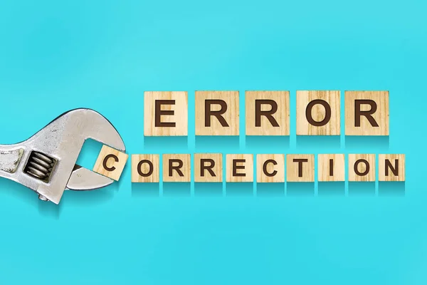 Fehlerkorrektur, Wort auf Holzklötzen geschrieben, verstellbarer Schraubenschlüssel auf blauem Hintergrund. Fehlerkorrekturkonzept. — Stockfoto