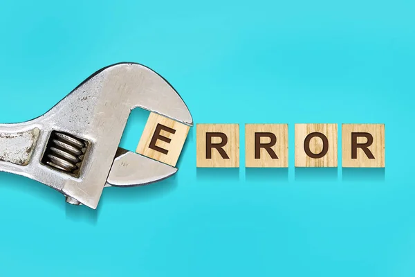 Error, word written on wooden blocks, adjustable wrench on blue background.Isolated. Error correction concept.
