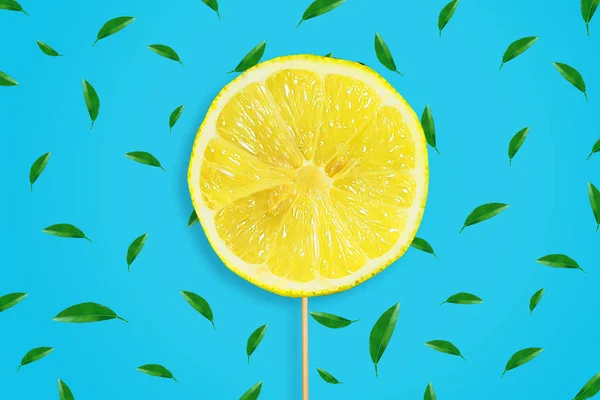 Uma fatia de limão fatiado num pau. Fundo azul com folhas. Frutos frescos e suculentos. Fundo das frutas . — Fotografia de Stock