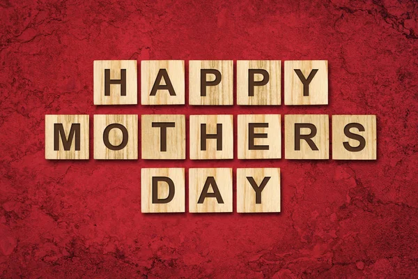 Glücklicher Muttertag, Wort auf Holzklötzen geschrieben. roter Hintergrund Gratulationshintergrund. Urlaubskarte. — Stockfoto