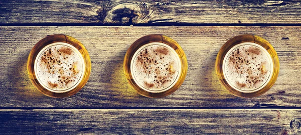 Tres vasos de cerveza fría y patatas fritas sobre un fondo de madera. Vista superior. Copiar espacio. Bebidas frías de verano . —  Fotos de Stock