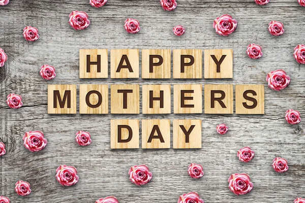 Glücklicher Muttertag, Wort auf Holzklötzen geschrieben. Schöne Rosen. Holzuntergrund. Glückwunsch-Hintergrund. Urlaubskarte. — Stockfoto