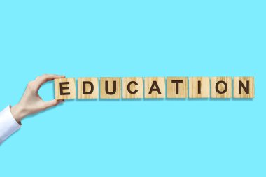 Eğitim kavramı. Kadın el ahşap bloklar üzerinde alfabe dışında Word yapar. Mavi arka plan. Izole.