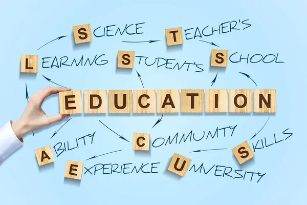 Education concept. Female hand makes up Word out of the alphabet on wooden blocks. Blue background. — Stock Photo, Image