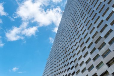 Bulutlu bir gökyüzüne karşı modern bir metal binanın cephesi. Alt görünüm Mimarisi