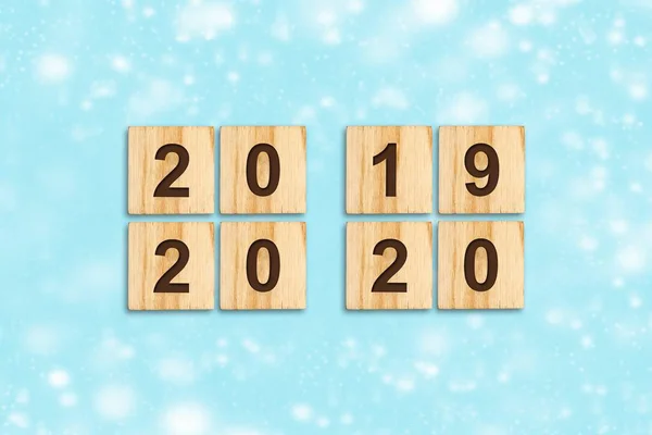 Happy New Year 2020. 2020, 2019 numbers on wooden blocks on a blue background. Happy new year greeting card