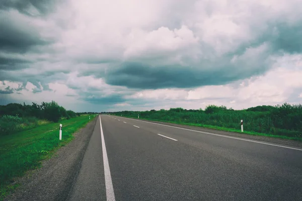 Dálnice jde na horizont. Krásná zamračená obloha. Zázemí pro cestování autem. Tonované Foto. — Stock fotografie